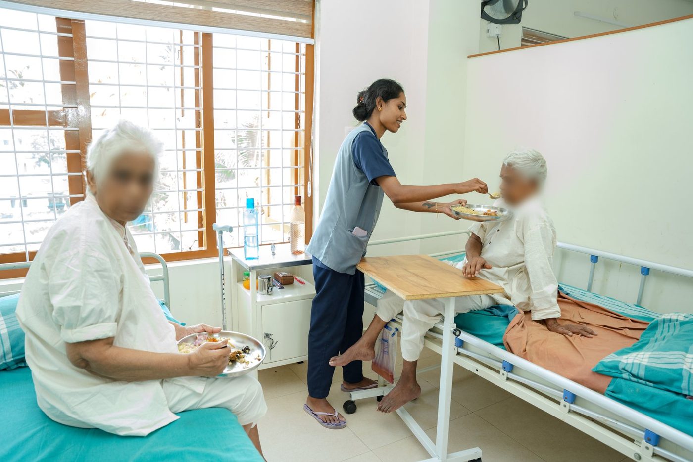 A nurse helping a resident with her meal in the women's ward